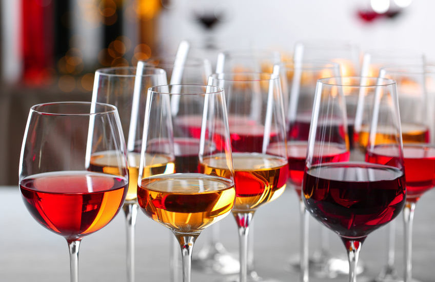 Glasses with different wines on blurred background, closeup