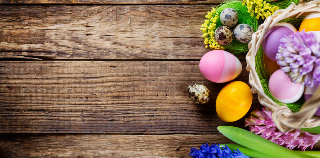 Easter decorations  on wooden table, colored eggs and flowers. Top view